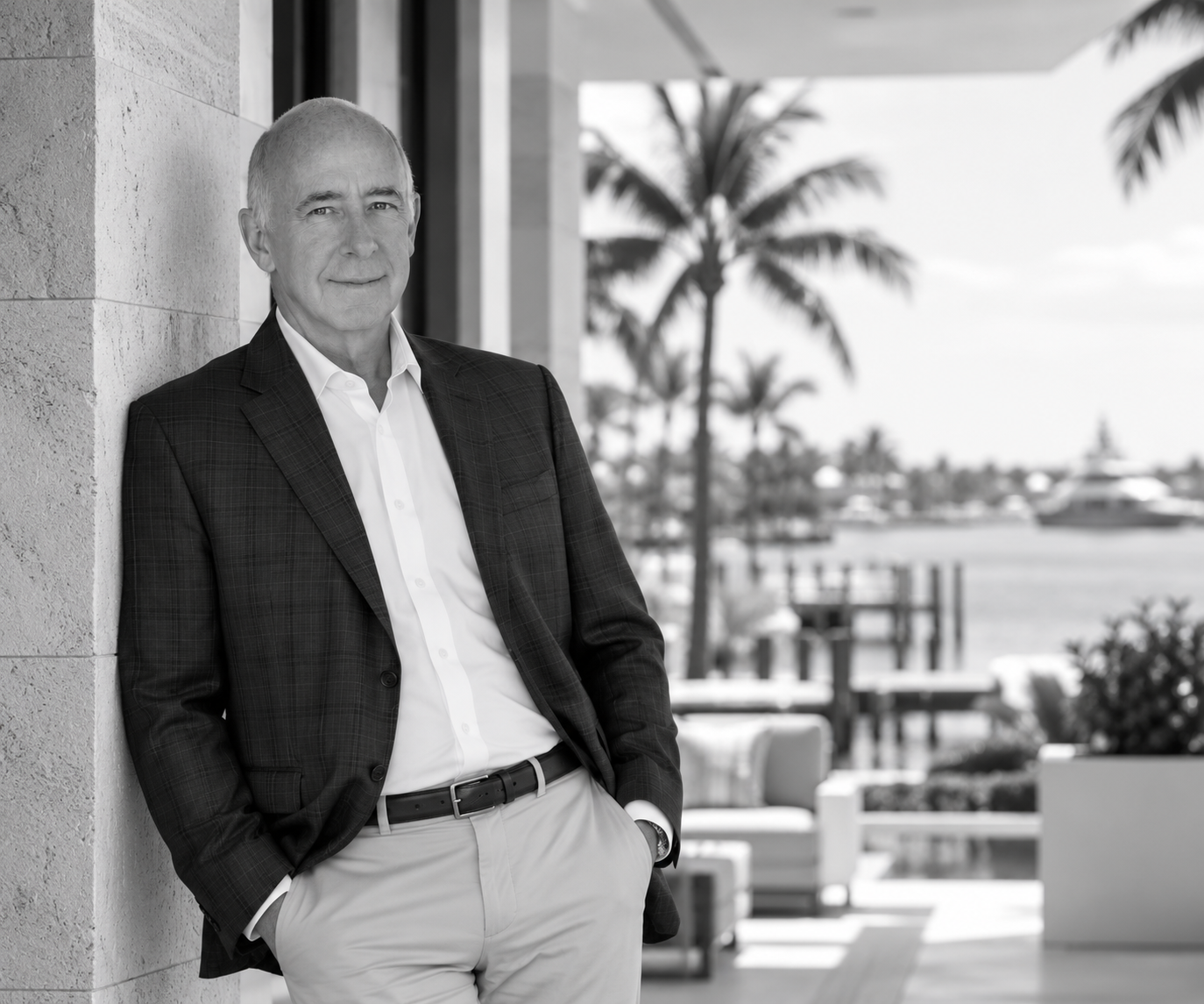 Black-and-white portrait of David Abernathy standing beside an architectural column, with palms and a waterfront behind him